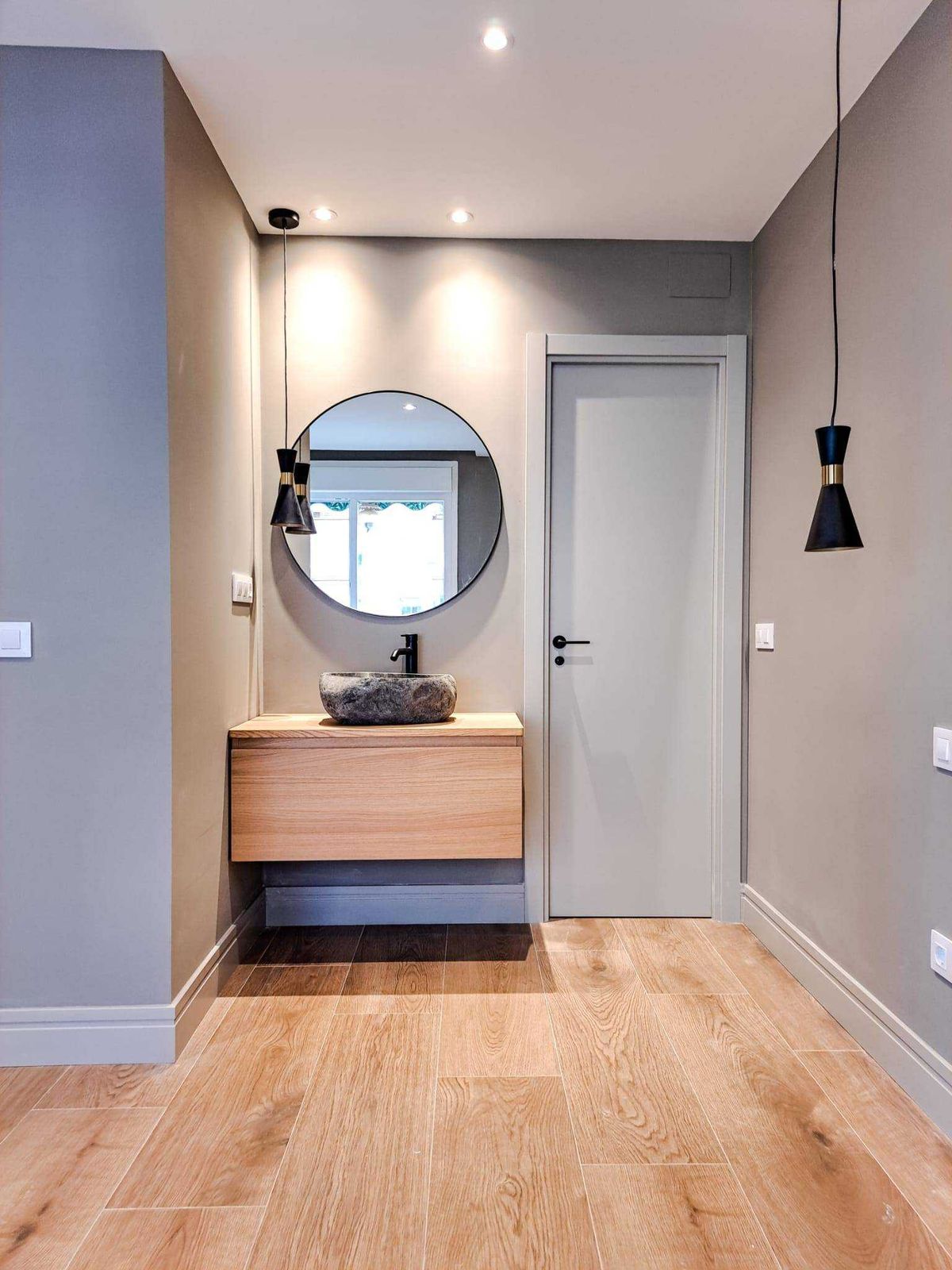 Cocina abierta con península de frentes de madera y encimera oscura, suelo de roble y paredes gris humo en una reforma integral de 70 m² en Cuatro Caminos, Madrid